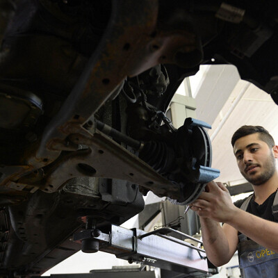 TO GO WITH AFP STORY by MATHILDE RICHTER - Picture taken on July 14, 2015 shows Syrian refugee George Romanos working on a car at a workshop in Bobingen, southern Germany, on July 14, 2015. Like a growing number of German employers, garage-owner Robert Menhofer has decided to give a young refugee a chance and is lavish in his praise for George Romanos, a young trainee from Syria.     AFP PHOTO / CHRISTOF STACHE